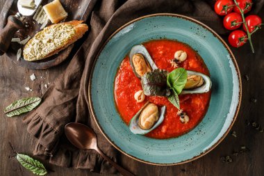 Koyu ahşap zemin üzerinde midye, kalamar ve peynirli parmesan soslu domates çorbası. Deniz ürünleri, sağlıklı yiyecekler, manzaralı.