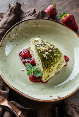 Kremalı yeşil çay keki, fındık, çilek reçeli ve ahşap zemin üzerinde nane şekeri. Lezzetli tatlılar ve tatlı, yakın çekim.