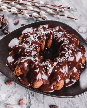 Paskalya kek çikolata, Hindistan cevizi, bir taş zemin üzerine bahar çiçekleri ile. Mutlu Paskalya kutlamaları