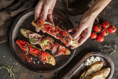Prosciutto, domates, parmesan peyniri, sos sosu, ahşap arka planda ciabatta ekmeğinde ızgara biber. Sandviç seti şarap, üst manzara.