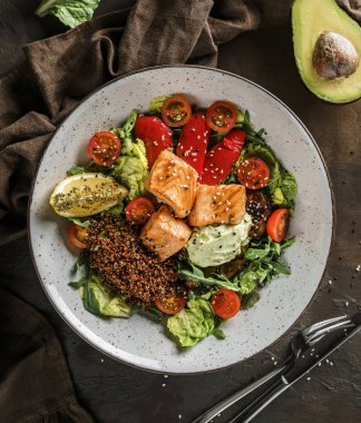 Somon filetosu, kinoa, avokado sosu, ızgara biber, domates, marul, ahşap zemin üzerinde roka ile sağlıklı salata. Sağlıklı yemek, temiz yemek, Buda kasesi, diyet, üst manzara.
