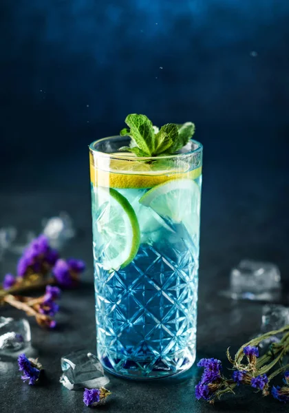 Cocktail de lagoa azul fresco com limão, hortelã e gelo em vidro jar sobre fundo azul escuro. Estúdio tiro de bebida em movimento de congelamento, gotas voando. Bebida fria de verão e coquetel — Fotografia de Stock