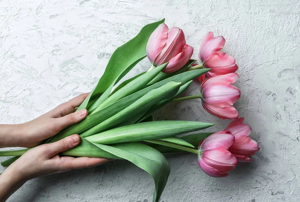 Mãos segurando flores de tulipas rosa no fundo branco. Cartão para o Dia das Mães, 8 de Março, Feliz Páscoa. À espera da Primavera. Cartão de felicitações. Deitado plano, vista superior — Fotografia de Stock