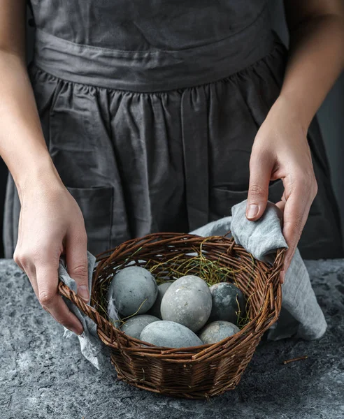Női kéz fonott kosárral, húsvéti tojással az asztalon. Kellemes húsvéti ünnepeket, szelektív fókuszt — Stock Fotó