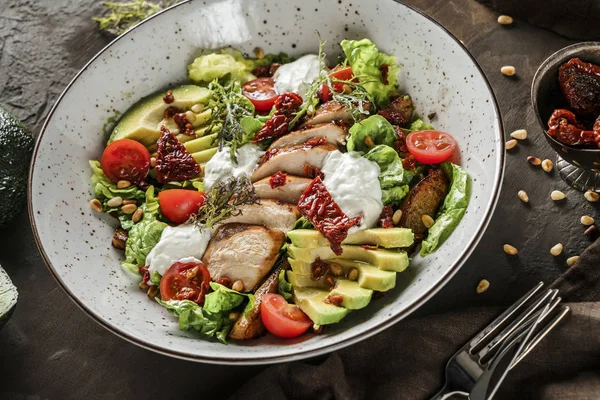 Gesunder Salat mit Hähnchenfilet, Avocado, Tomaten, Salat, Gemüse, Pinienkernen und Soße in einer Schüssel auf hölzernem Hintergrund. gesunde Ernährung, saubere Ernährung, Diät, Buddha-Schale, Nahaufnahme — Stockfoto