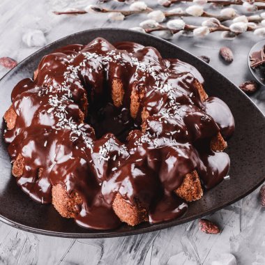 Paskalya kek çikolata, Hindistan cevizi, bir taş zemin üzerine bahar çiçekleri ile. Mutlu Paskalya kutlamaları