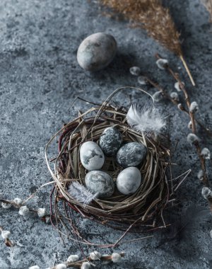 Kuş yuvasında paskalya yumurtaları ve mavi arka planda tüyleri var. Mutlu Paskalyalar, kapatıyoruz.