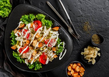 Sağlıklı Sezar salatası domatesli, marullu, kızarmış tavuk göğsü, peynirli parmesan peyniri ve siyah taş kaplamalı sos. Sağlıklı yemek, en iyi manzara.