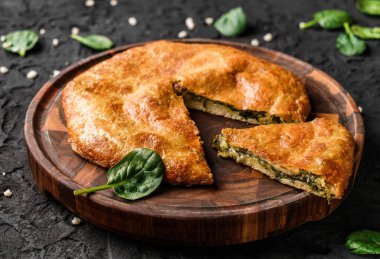 Gürcistan khachapuri 'si. Tahta kesme tahtasının üzerinde peynirli ve ıspanaklı yassı ekmek. Ev yapımı yemek.
