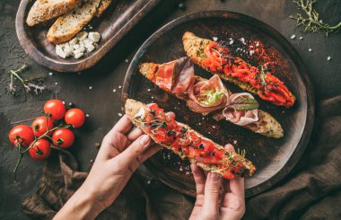 Prosciutto, domates, parmesan peyniri, sos sosu, ahşap arka planda ciabatta ekmeğinde ızgara biber. Sandviç seti şarap, üst manzara.