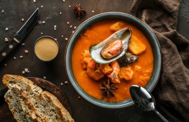 Midyeli domates çorbası, kalamar, karides ve peçeteli ahşap kaplama. Deniz ürünleri, sağlıklı yiyecekler, manzaralı.