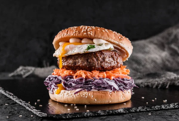 Burger Wołowy Kapustą Marchewką Smażonymi Jajkami Sosem Łupkowym Czarnym Tle — Zdjęcie stockowe