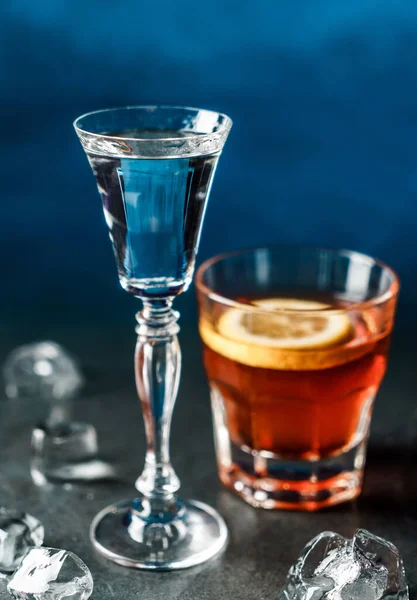 Classic alcoholic cocktails in shot glasses or shooters on dark blue background. Drink and beverages
