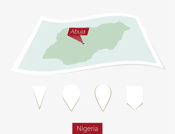 Böjda papperskarta över Nigeria med huvudstaden Abuja på grå bakgrund. — Stock vektor