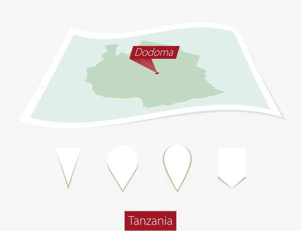 Mapa en papel curvado de Tanzania con la capital Dodoma sobre fondo gris . — Vector de stock