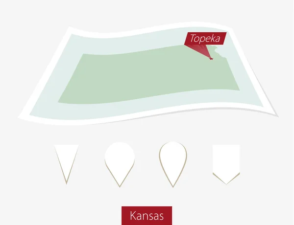 Gebogene Papierkarte des Bundesstaates Kansas mit Hauptstadt-Topeka auf grauem Hintergrund. — Stockvektor