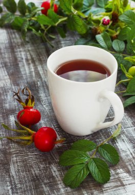 Bir dogrose bir kupa meyve ahşap bir zemin üzerine çaydan