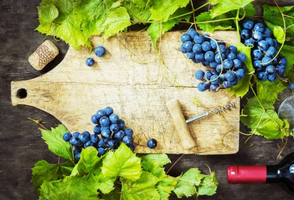 Uvas, una botella de vino, corchos y sacacorchos en una mesa vieja de madera, estilo rústico — Foto de Stock