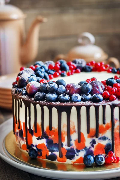 Bright festive cake with berries and chocolate on a dark wood background, rustic style — Stock Photo, Image