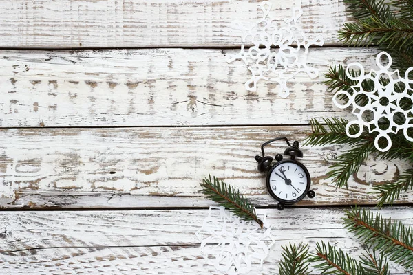 Klok en de spar takken op een witte houten achtergrond — Stockfoto