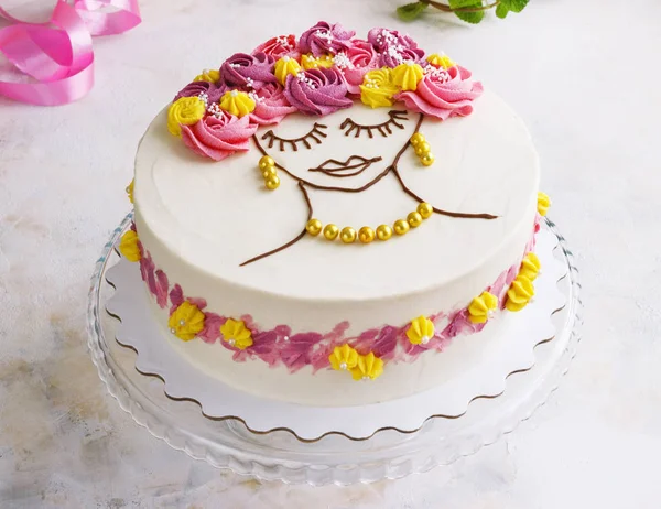 Festive cake with cream flowers and a girl face on a light background — Stock Photo, Image
