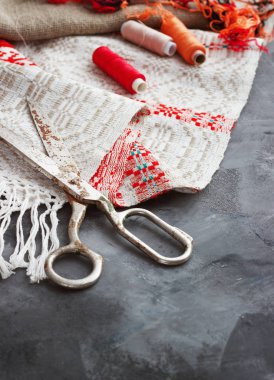 Makas, bobin iplik ve iğneler, kumaş çizgili. Eski dikiş araçlar arka planda. Antika arka plan