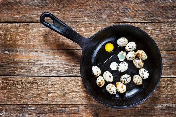 Αυγά ορτυκιού σε τηγάνι από χυτοσίδηρο σε παλιό ξύλινο τραπέζι, ρετρό στυλ — Φωτογραφία Αρχείου