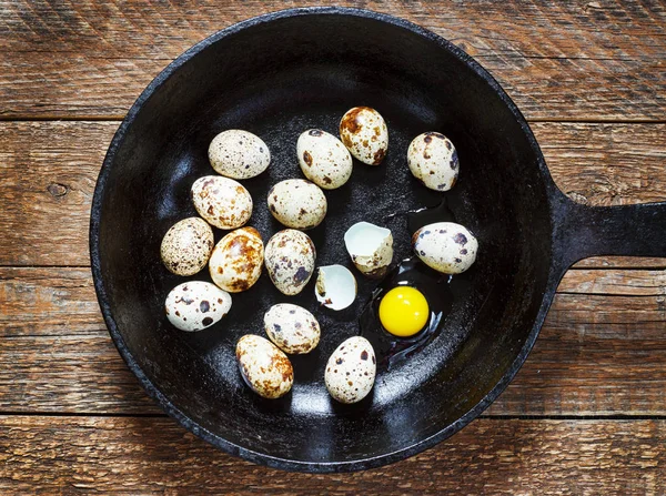 Αυγά ορτυκιού σε τηγάνι από χυτοσίδηρο σε παλιό ξύλινο τραπέζι, ρετρό στυλ — Φωτογραφία Αρχείου