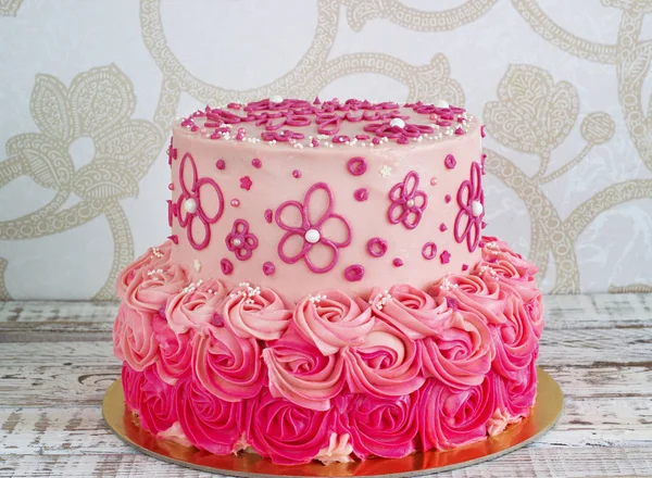 Festive, pink cake for a girl with cream roses on a light background