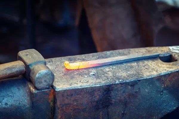 Кузнец обрабатывает металл с молотком на наковальне — стоковое фото