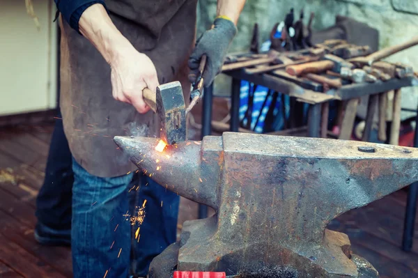 Smeden metallbearbetning med hammaren på städet — Stockfoto