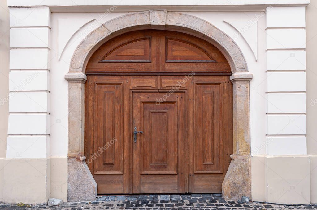 Old wooden door close-up on a background of a wall . Old house exterior