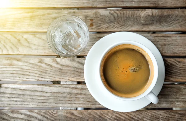 Tasse à café blanche et eau en verre sur table en bois . — Photo