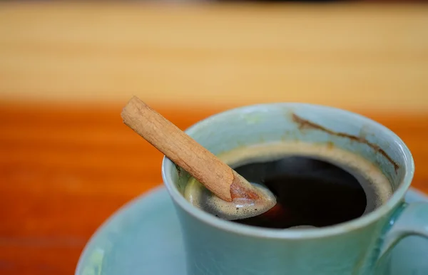 Tasse à café sur table en bois avec cannelle dans le café . — Photo