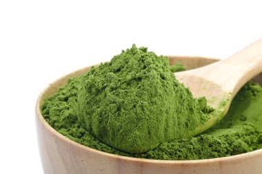 Tahta kaşık beyaz zemin üzerine yeşil çay tozu.