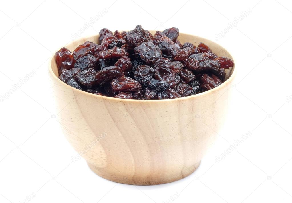 Dried grapes in wood bowl on white background.