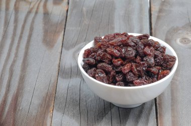 Ahşap zemin üzerinde beyaz Kupası'nda kuru üzüm.