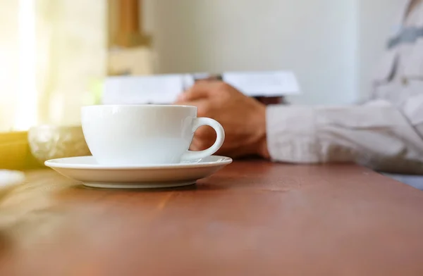 Man läser en bok med vita kaffe kopp front placera. — Stockfoto