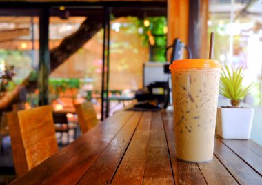 Kahve fincanı bulanık kafe ile ahşap zemin üzerinde buz.