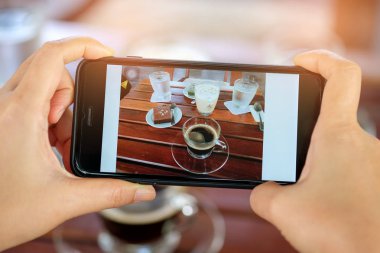 Elinde kahve ve kek tablo ile Smartphone.