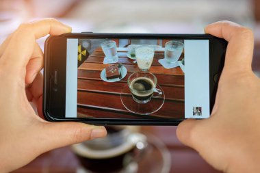 Elinde kahve ve kek tablo ile Smartphone.