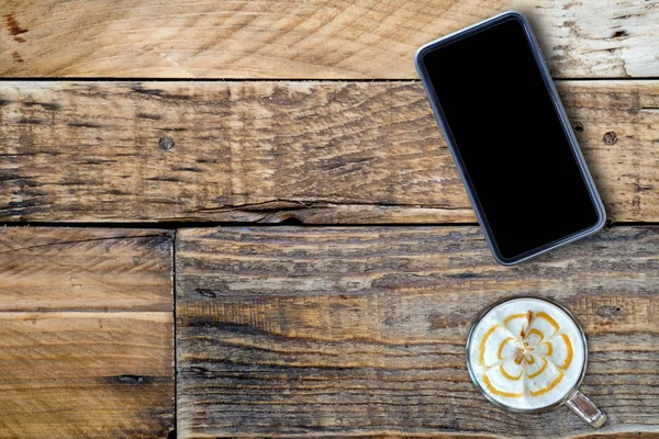 Smart telefon med kaffe sent på trä. — Stockfoto