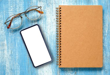 Defter ve ahşap zemin üzerinde gözlük ile akıllı telefon.