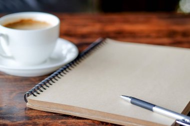 Üstünde kahve ile defter kalem.