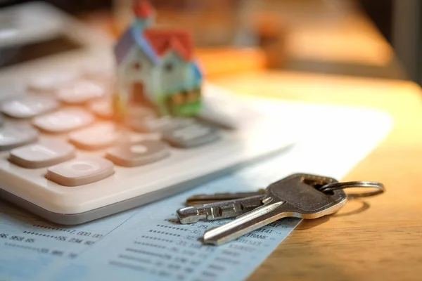 Modelo de casa y llave con calculadora en banco de libros . —  Fotos de Stock