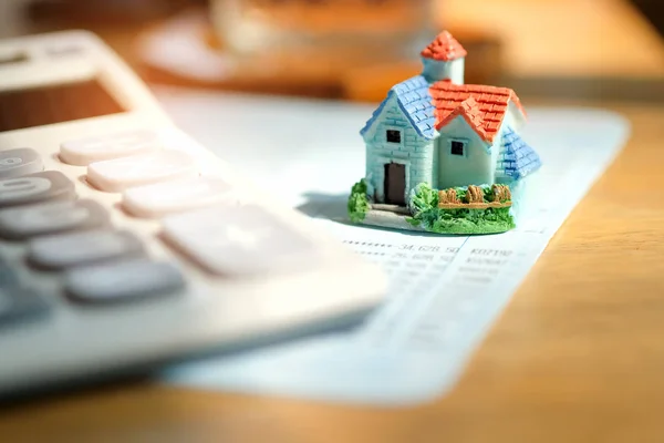 Huis model met calculator op boek bank. — Stockfoto