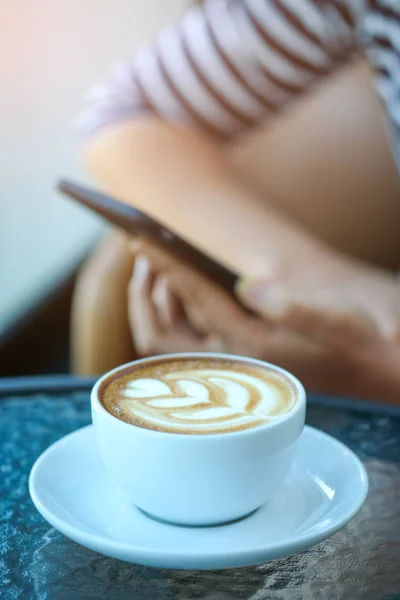 Kvinnor spela smart telefon med kaffe hjärtat latte i hand sätta på — Stockfoto