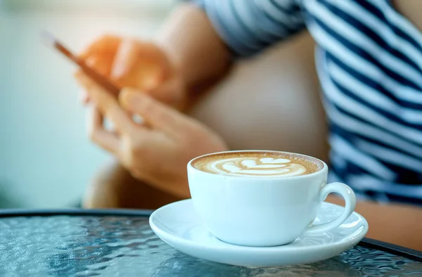Kvinnor spela smart telefon med kaffe hjärtat latte i hand sätta på — Stockfoto