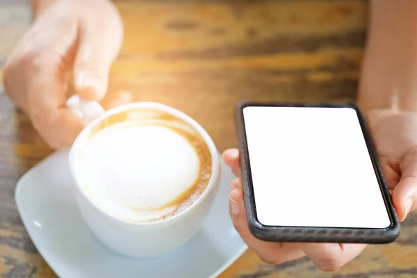 Vit kaffekopp i handen med smart phone. — Stockfoto