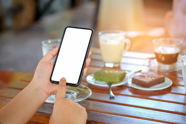 Teléfono inteligente en la mano con café y pastel en la mesa . —  Fotos de Stock